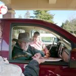 elderly couple receives cookies and hot chocolate at the david carrier cookie and cocoa drive-by